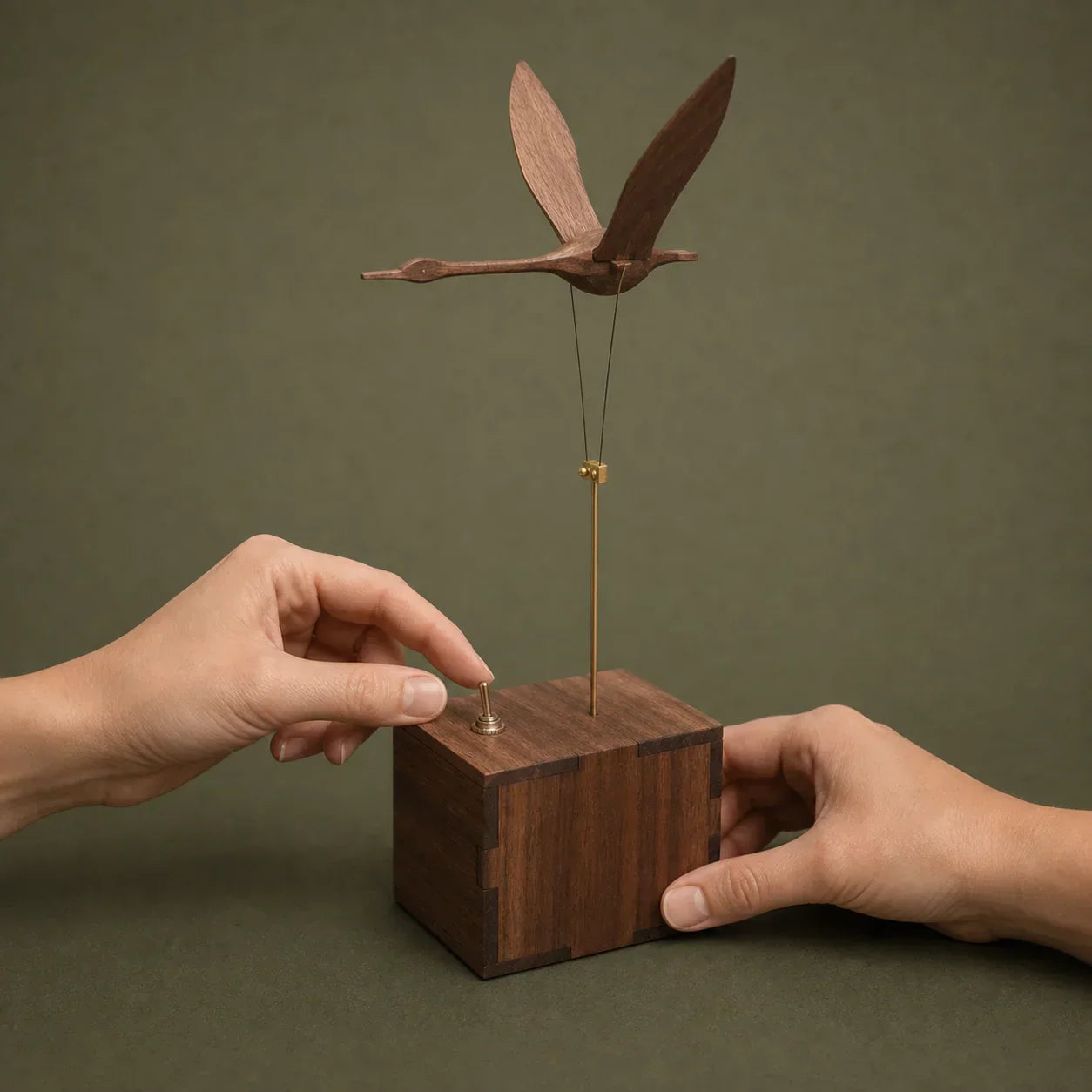 Hand operating the cord slider on a Flying Swan wooden kinetic sculpture